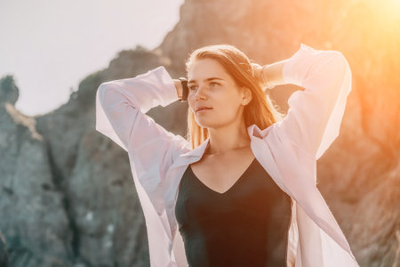Young woman in black bikini and white shirt on Beach. Girl lying on pebble beach and enjoying sun....
