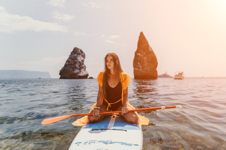 Woman sea sup. Close up portrait of happy young caucasian woman with long hair looking at camera and smiling. Cute woman portrait in bikini posing on sup board in the seaの写真素材