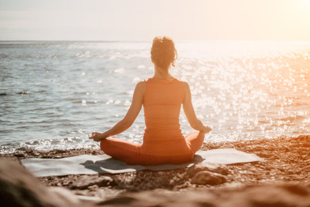 Woman sea yoga. Selective focus. Young beautiful caucasian woman in a red suit practicing yoga on the beach at sunrise near the sea. Yoga. Healthy lifestyle. Meditation concept.の写真素材