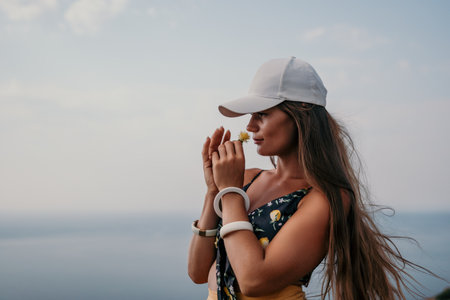 Woman travel sea. Happy tourist taking picture outdoors for memories. Woman traveler looks at the edge of the cliff on the sea bay of mountains, sharing travel adventure journeyの写真素材