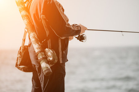 Man hobby fishing on sea tightens a fishing line reel of fish summer. Calm surface sea. Close-up of a fisherman hands twist reel with fishing line on a rod. Fishing in the sea outdoors. Slow motion.の写真素材