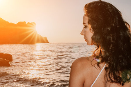 Woman sea yoga. Happy woman in white swimsuit and boho style braclets practicing outdoors on yoga mat by sea on sunset. Women yoga fitness routine. Healthy lifestyle, harmony and meditationの写真素材