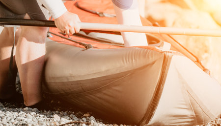 Happy couple kayaks in an inflatable kayak on the sea at sunset. Couple kanoeing in the sea near the island with mountains. People kayaking in life jackets sail. Back viewの写真素材
