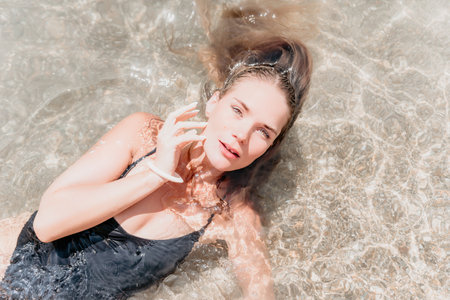 Woman summer travel sea. Happy tourist enjoy taking picture outdoors for memories. Woman traveler posing on the beach at sea surrounded by volcanic mountains, sharing travel adventure journeyの写真素材