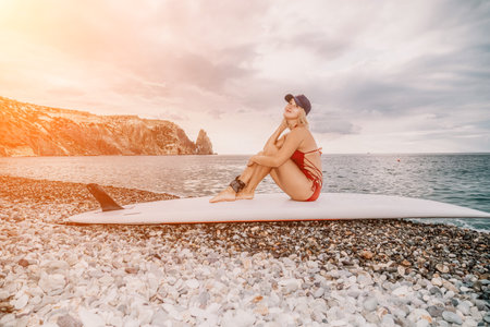 Woman in red bikini on Beach. Happy lady with blond hair in bathing suit chilling and sunbathing by turquoise sea ocean on sunset. Holiday, vacation and recreational concept. Close upの写真素材