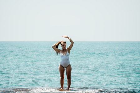 Woman sea yoga. Back view of free calm happy satisfied woman with long hair standing on top rock with yoga position against of sky by the sea. Healthy lifestyle outdoors in nature, fitness conceptの写真素材