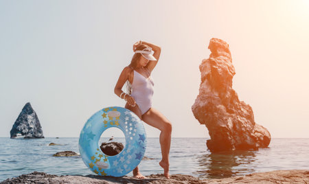 Woman summer sea. Happy woman swimming with inflatable donut on the beach in summer sunny day, surrounded by volcanic mountains. Summer vacation concept.の写真素材