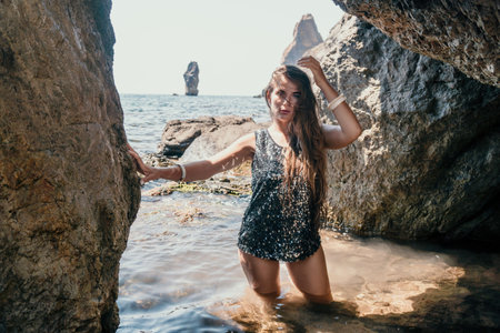 Woman summer travel sea. Happy tourist enjoy taking picture outdoors for memories. Woman traveler posing on the beach at sea surrounded by volcanic mountains, sharing travel adventure journeyの写真素材