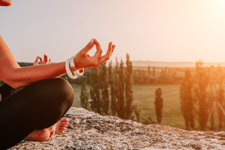 Fitness woman. Well looking middle aged woman with long hair, fitness instructor in leggings and tops doing stretching and pilates on the rock near forest. Female fitness yoga routine concept.の写真素材
