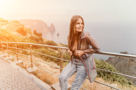Woman rain umbrella. Happy woman portrait wearing a raincoat with transparent umbrella outdoors on rainy day in park near sea. Girl on the nature on rainy overcast day.の写真素材