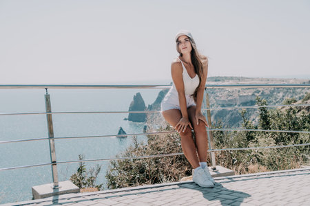 Woman summer travel sea. Happy tourist enjoy taking picture outdoors for memories. Woman traveler posing over sea bay surrounded by volcanic mountains, sharing travel adventure journeyの写真素材
