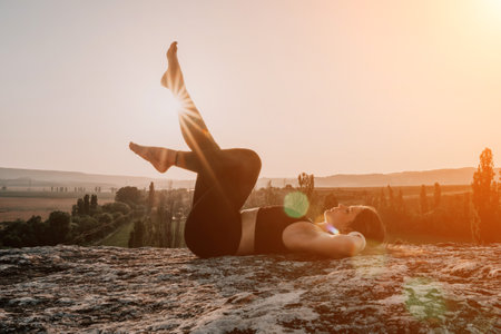 Fitness woman. Well looking middle aged woman with long hair, fitness instructor in leggings and tops doing stretching and pilates on the rock near forest. Female fitness yoga routine concept.の写真素材