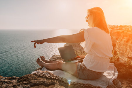 Woman sea laptop. Business woman working on laptop by sea at sunset. Close up on hands of pretty lady typing on computer outdoors summer day. Freelance, digital nomad, travel and holidays concept.の写真素材
