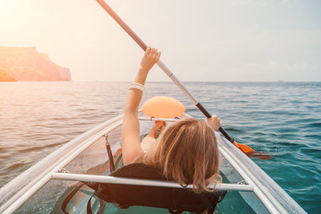Woman in kayak back view. Happy young woman with long hair floating in transparent kayak on the crystal clear sea. Summer holiday vacation and cheerful female people relaxing having fun on the boatの写真素材