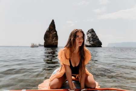 Woman sea sup. Close up portrait of happy young caucasian woman with long hair looking at camera and smiling. Cute woman portrait in bikini posing on sup board in the seaの写真素材