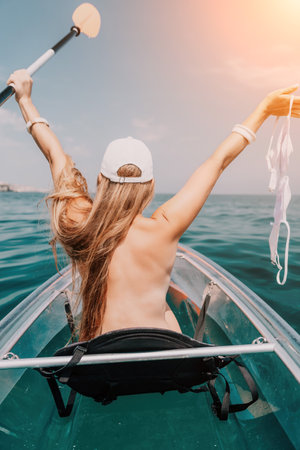 Woman in kayak back view. Happy young woman with long hair floating in transparent kayak on the crystal clear sea. Summer holiday vacation and cheerful female people relaxing having fun on the boatの写真素材
