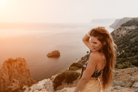Woman travel sea. Happy tourist taking picture outdoors for memories. Woman traveler looks at the edge of the cliff on the sea bay of mountains, sharing travel adventure journeyの写真素材