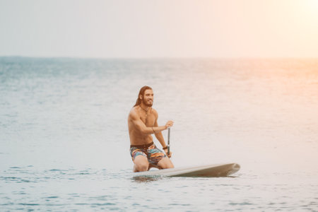 Sea woman and man on sup. Silhouette of happy young woman and man, surfing on SUP board, confident paddling through water surface. Idyllic sunset. Active lifestyle at sea or river.の写真素材
