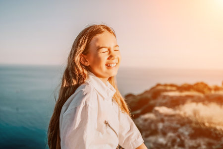 Adorable teenage girl outdoors enjoying sunset at beach on summer day. Close up portrait of smiling young romantic teenager girl with long hair on beach at summer evening. Travel and holidaysの写真素材