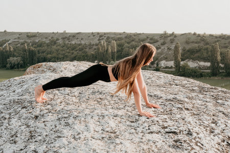 Fitness woman. Well looking middle aged woman with long hair, fitness instructor in leggings and tops doing stretching and pilates on the rock near forest. Female fitness yoga routine concept.の写真素材