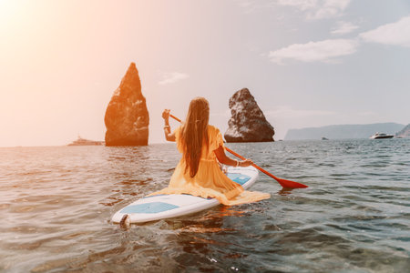 Woman sea sup. Close up portrait of happy young caucasian woman with long hair looking at camera and smiling. Cute woman portrait in bikini posing on sup board in the seaの写真素材
