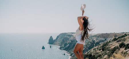 Woman summer travel sea. Happy tourist enjoy taking picture outdoors for memories. Woman traveler posing over sea bay surrounded by volcanic mountains, sharing travel adventure journeyの写真素材