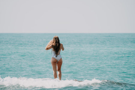 Woman sea yoga. Back view of free calm happy satisfied woman with long hair standing on top rock with yoga position against of sky by the sea. Healthy lifestyle outdoors in nature, fitness conceptの写真素材