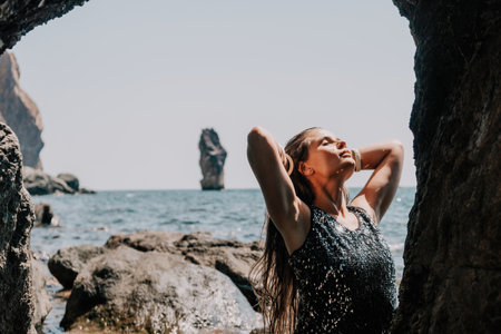 Woman summer travel sea. Happy tourist enjoy taking picture outdoors for memories. Woman traveler posing on the beach at sea surrounded by volcanic mountains, sharing travel adventure journeyの写真素材