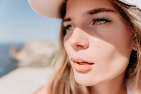 Woman travel portrait. Happy woman with long hair looking at camera and smiling. Close up portrait cute woman in a mint long dress posing on a volcanic rock high above the seaの写真素材
