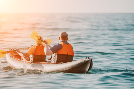 Happy couple kayaks in an inflatable kayak on the sea at sunset. Couple kanoeing in the sea near the...