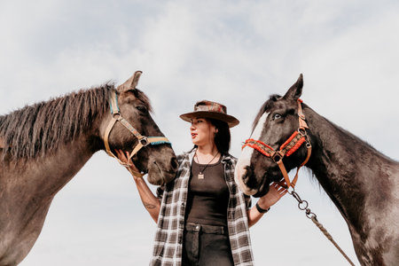 Young happy woman in hat with her horse in evening sunset light. Outdoor photography with fashion model girl. Lifestyle mood. Concept of outdoor riding, sports and recreation.の写真素材