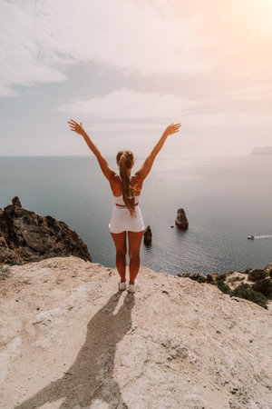 Woman travel sea. Young Happy woman posing on a beach over the sea on background of volcanic rocks, like in Iceland, sharing travel adventure journeyの写真素材