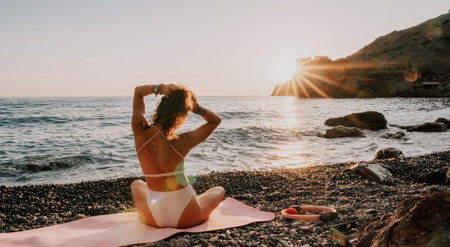 Woman sea yoga. Happy woman in white swimsuit and boho style braclets practicing outdoors on yoga...