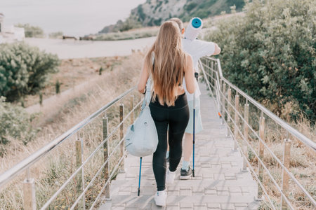 Happy Middle aged couple or friends practicing nordic walking in park near sea. Mature couple with trekking poles walking, practicing Nordic walking outdoors. Aging youthfully and sport conceptの写真素材