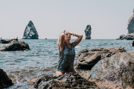 Woman summer travel sea. Happy tourist enjoy taking picture outdoors for memories. Woman traveler posing on the beach at sea surrounded by volcanic mountains, sharing travel adventure journeyの写真素材