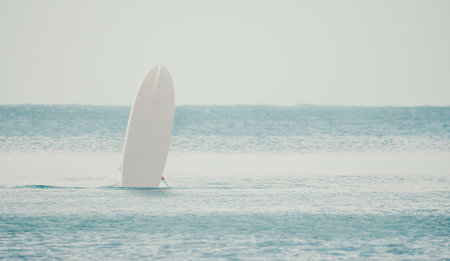 Sea man sup. Asian athlete man swimming in sea and paddleboarding at summer sunset. Healthy strong male enjoy outdoor active lifestyle and water sports on holiday vacation.の写真素材