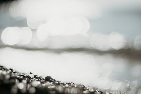 Blurred golden sea at sunset. The sun reflects and sparkles on the waves with bokeh, illuminating the golden sea. Holiday recreation concept. Abstract nautical summer ocean sunset nature background.の写真素材