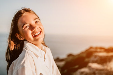 Adorable teenage girl outdoors enjoying sunset at beach on summer day. Close up portrait of smiling young romantic teenager girl with long hair on beach at summer evening. Travel and holidaysの写真素材
