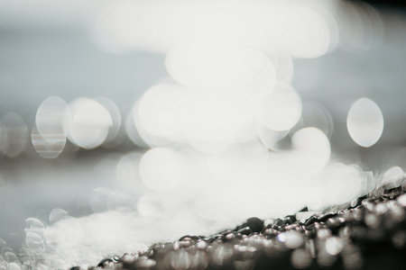 Blurred golden sea at sunset. The sun reflects and sparkles on the waves with bokeh, illuminating the golden sea. Holiday recreation concept. Abstract nautical summer ocean sunset nature background.の写真素材