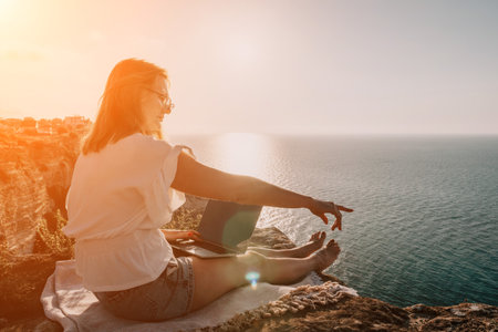 Woman sea laptop. Business woman working on laptop by sea at sunset. Close up on hands of pretty lady typing on computer outdoors summer day. Freelance, digital nomad, travel and holidays concept.の写真素材