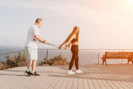 Happy Middle aged couple or friends practicing nordic walking in park near sea. Mature couple with...