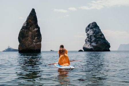 Woman sea sup. Close up portrait of happy young caucasian woman with long hair looking at camera and smiling. Cute woman portrait in bikini posing on sup board in the seaの写真素材