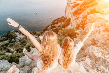 Sea family vacation together, happy mom and teenage daughter hugging and smiling together over sunset sea view. Beautiful woman with long hair relaxing with her child. Concept of happy friendly family.の写真素材
