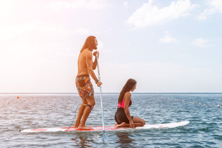 Sea woman and man on sup. Silhouette of happy young woman and man, surfing on SUP board, confident...