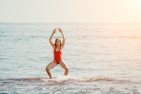 Woman sea yoga. Happy woman meditating in yoga pose on the beach, ocean and rock mountains. Motivation and inspirational fit and exercising. Healthy lifestyle outdoors in nature, fitness concept.の写真素材