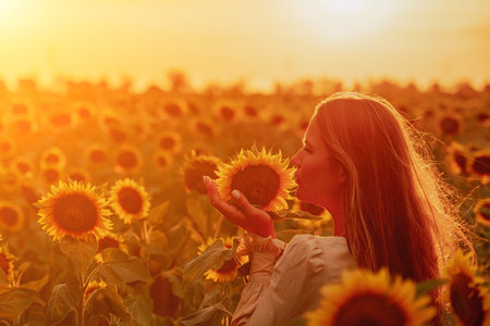 Woman in Sunflower Field: Happy girl in a straw hat posing in a vast field of sunflowers at sunset, enjoy taking picture outdoors for memories. Summer time.の写真素材