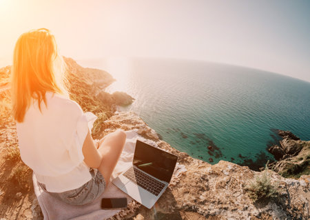 Woman sea laptop. Business woman working on laptop by sea at sunset. Close up on hands of pretty lady typing on computer outdoors summer day. Freelance, digital nomad, travel and holidays concept.の写真素材