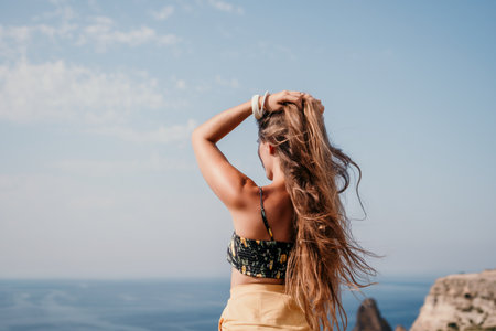 Woman travel sea. Happy tourist taking picture outdoors for memories. Woman traveler looks at the edge of the cliff on the sea bay of mountains, sharing travel adventure journeyの写真素材