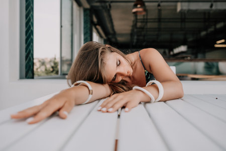 Happy woman portrait in cafe. Boho chic fashion style. Outdoor photo of young happy woman with long hair, sunny weather outdoors sitting in modern cafe.の写真素材