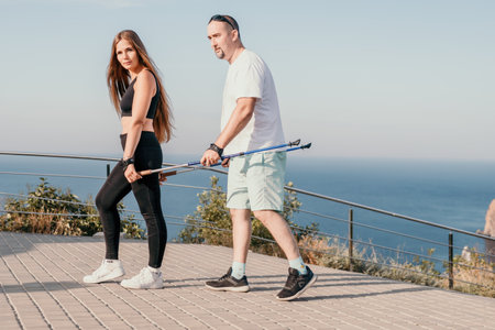 Happy Middle aged couple or friends practicing nordic walking in park near sea. Mature couple with...